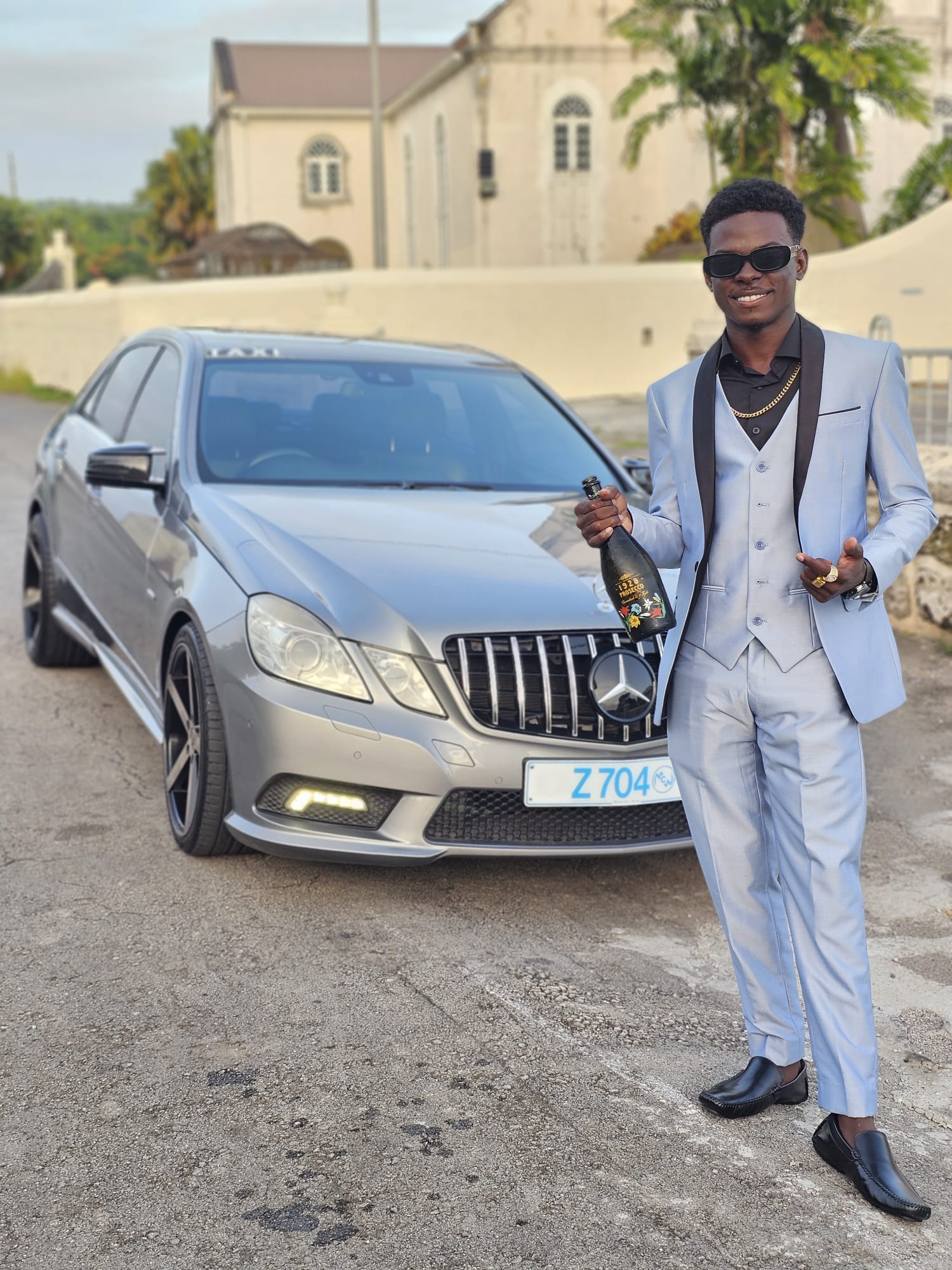 Chauffeur in a suit beside a Mercedes luxury sedan in Barbados