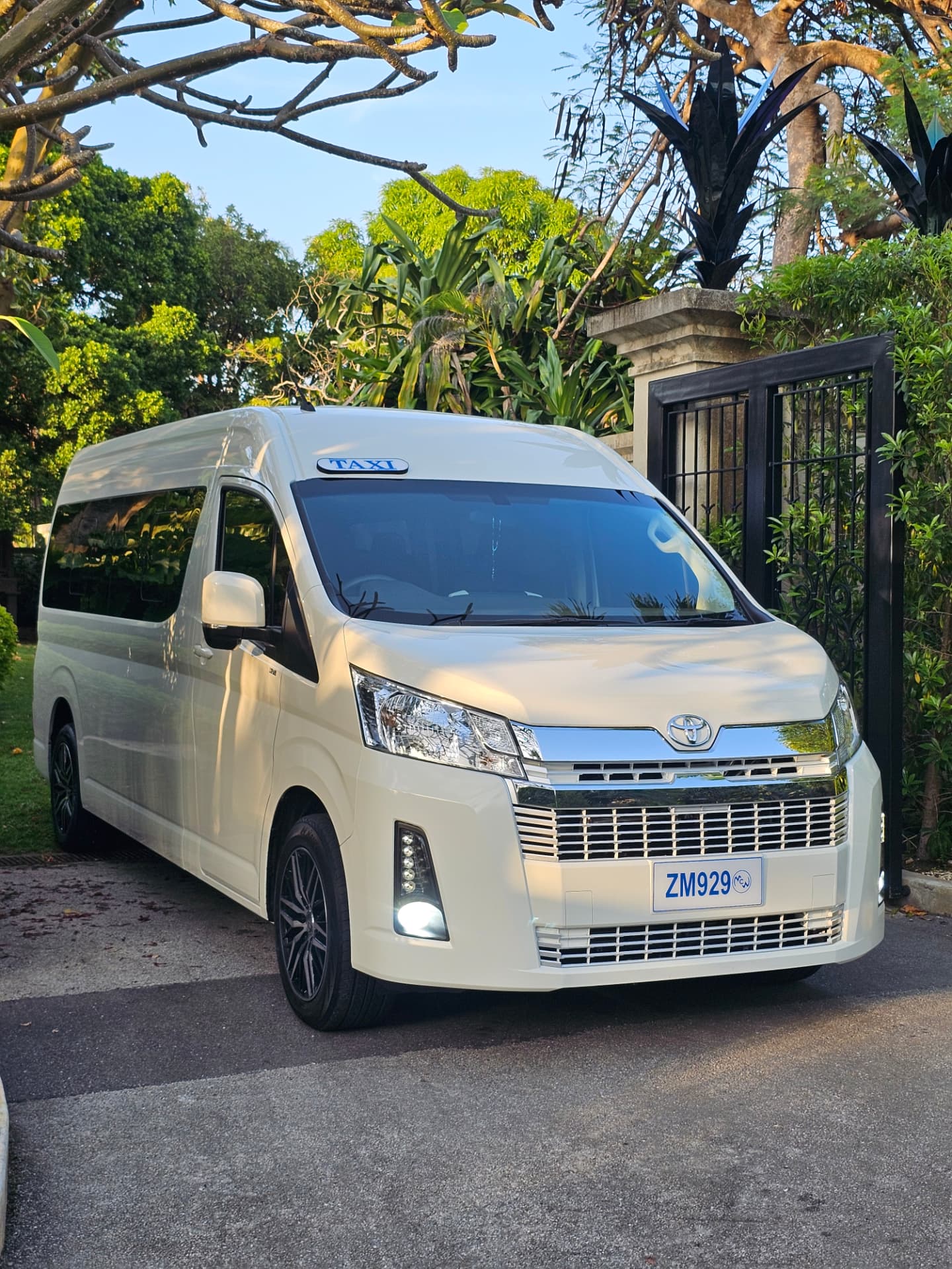 White Toyota luxury van taxi of Unique Chauffeurs at a Barbados villa gate