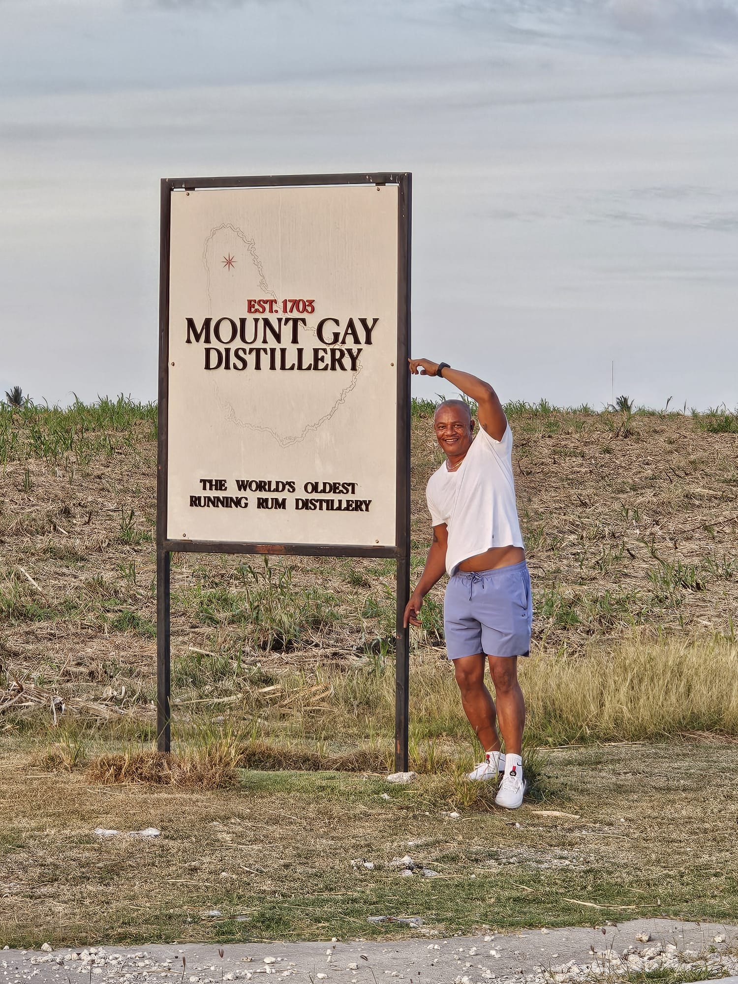 Visitor at the Mount Gay Rum Distillery sign on a Barbados island tour